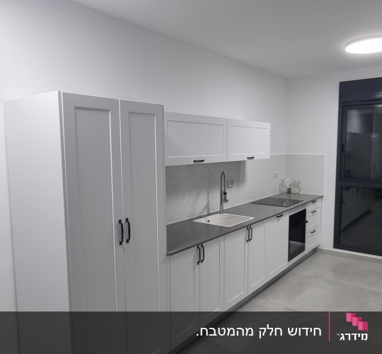מטבח מודרני עם ארונות לבנים ומשטח עבודה אפור